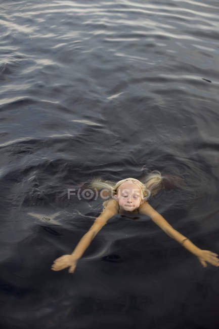 Girl with blonde hair swimming in lake — Stock Photo