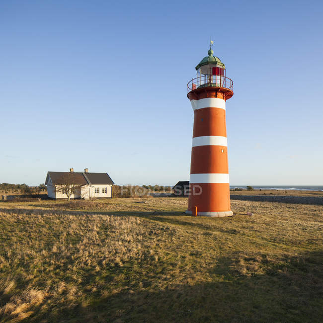 Red lighthouse and small house in bright sunlight — Stock Photo