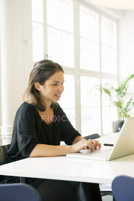 Young woman using laptop and smiling — Stock Photo
