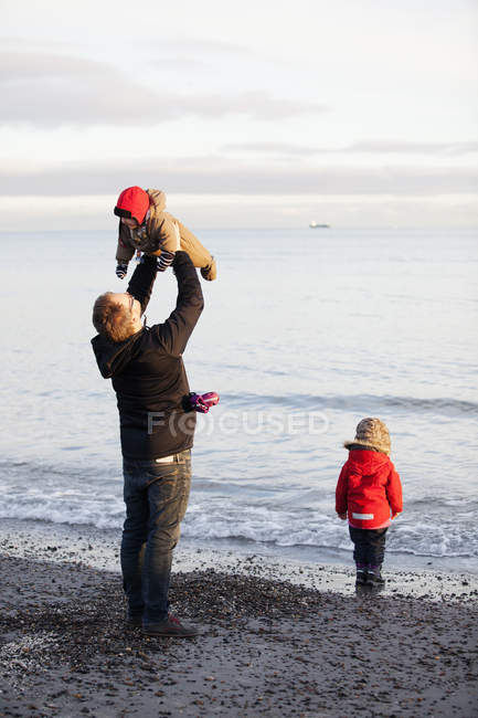 Батько з дочками, які грають на пляжі, вибірковий фокус — стокове фото