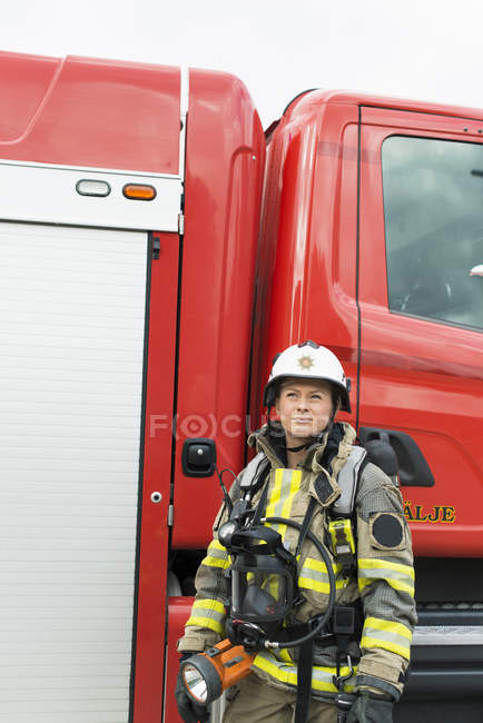 Жіночий пожежник, що стоїть біля пожежного двигуна — стокове фото