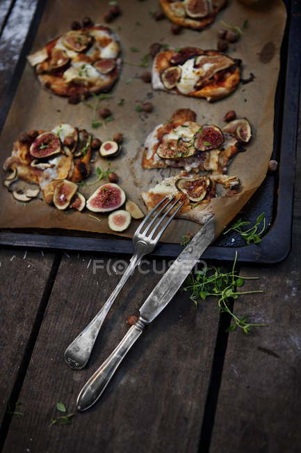 Повышенный вид на приготовленную пиццу на подносе со столовыми приборами — стоковое фото