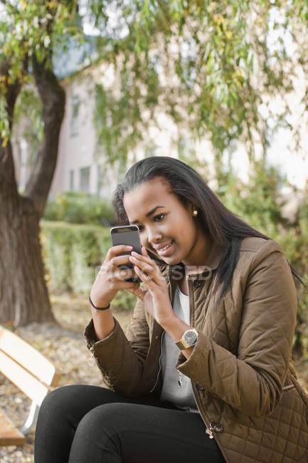 Seitenansicht eines Teenagermädchens beim SMS-Schreiben im Park — Stockfoto