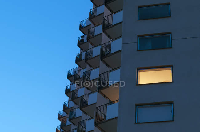 Moderna fachada de casa plana con cielo azul y una ventana iluminada al amanecer - foto de stock