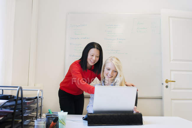 Mulher ajudando colega trabalhando no laptop, foco seletivo — Fotografia de Stock