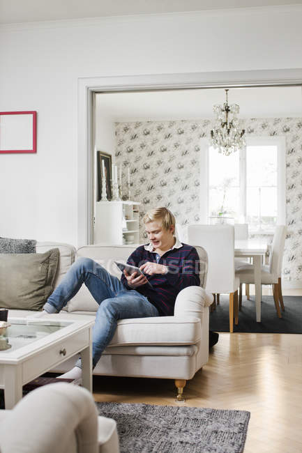 Adolescente usando tablet digital no sofá — Fotografia de Stock