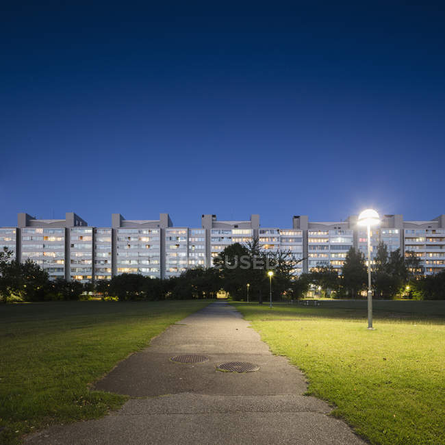 Flachhäuser mit beleuchteten Fenstern und Stadtteilpark — Stockfoto