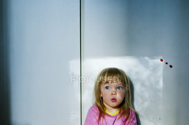 Girl with blonde hair watching light from window — Stock Photo