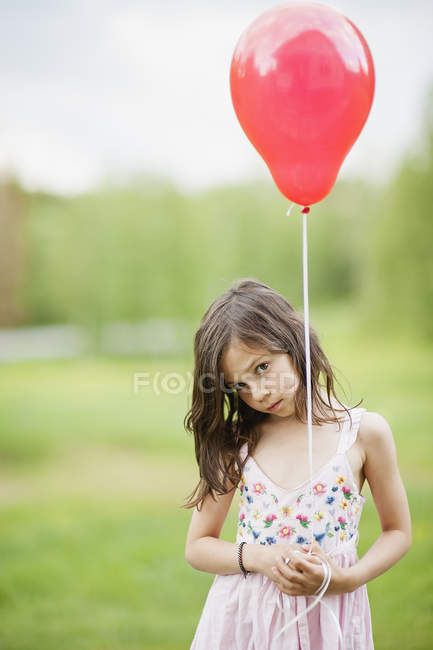 Linda chica sosteniendo globo rojo, enfoque selectivo - foto de stock
