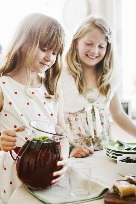Girls pouring juice at dining room, selective focus — Stock Photo