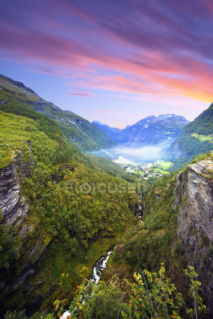 Montañas verdes y valle bajo cielo nublado del atardecer - foto de stock