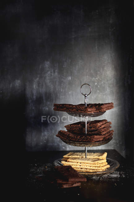 Biscoitos e biscoitos na mesa em pouca luz — Fotografia de Stock