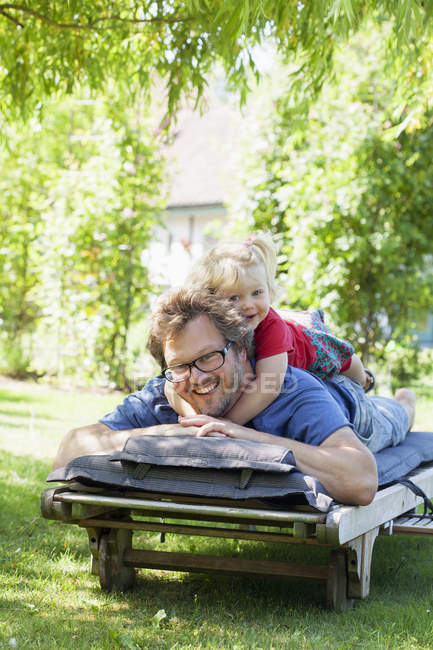 Portrait of daughter with father lying on deckchair — Stock Photo