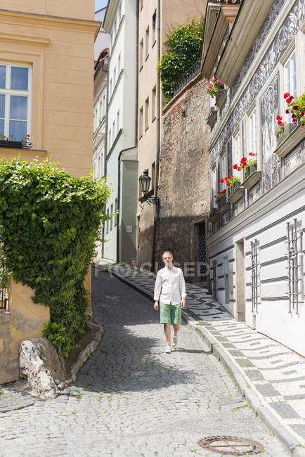 Человек, идущий по маленькой улице при ярком солнечном свете — стоковое фото