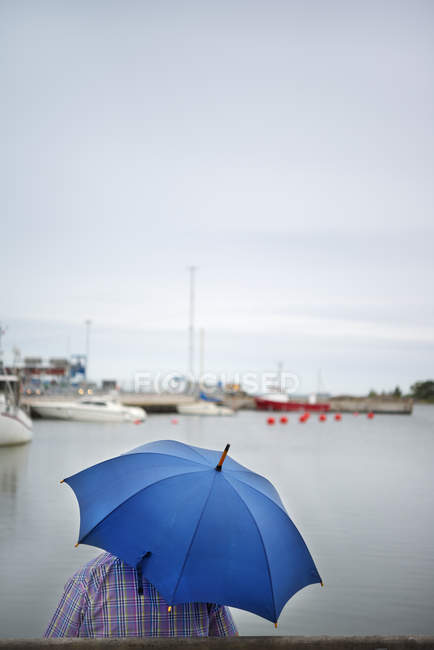 Man holding blue umbrella, focus on foreground — Stock Photo