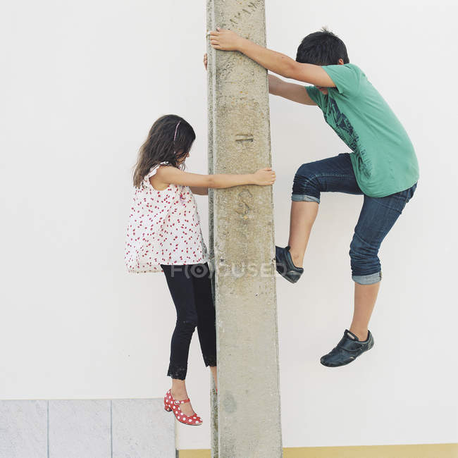 Vista lateral de niño y niña escalada post - foto de stock