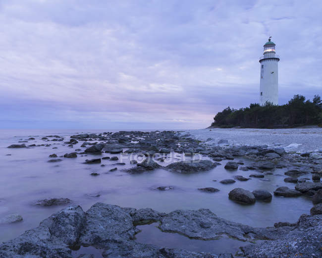 Long exposure shot of lighthouse on rocky seashore — Stock Photo