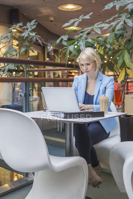 Giovane donna d'affari che utilizza il computer portatile in caffè — Foto stock