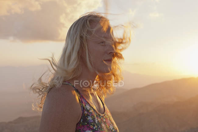 Turista femenina relajándose en el paisaje de montaña al atardecer - foto de stock