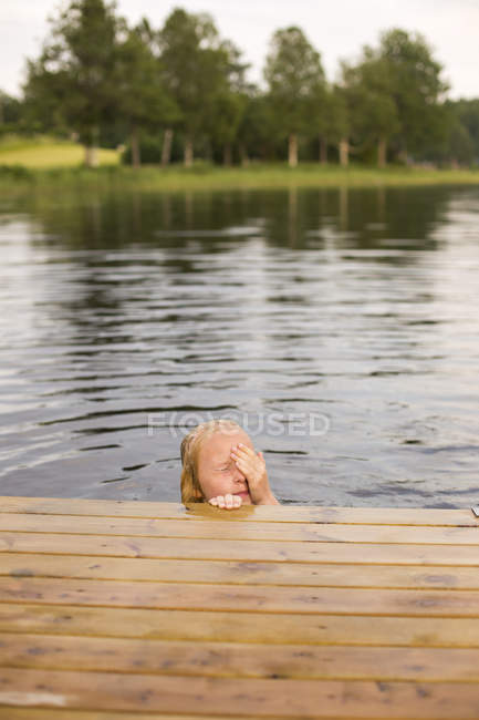Girl in lake drying off eyes with hand — Stock Photo