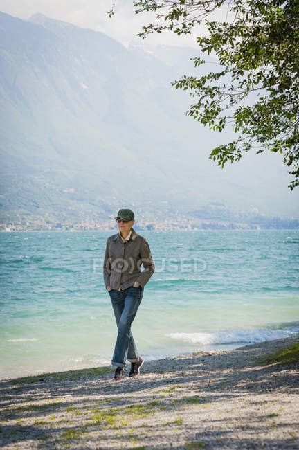 Femme marchant sur le bord du lac et regardant loin — Photo de stock