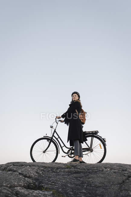 Вид збоку молодої жінки, що стоїть на велосипеді по скелі — стокове фото
