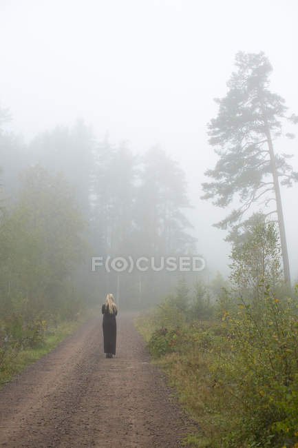 Mulher caminhando no nevoeiro no campo — Fotografia de Stock