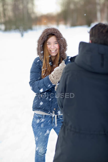 Portrait of young woman playing with snow balls with man, selective focus — Stock Photo
