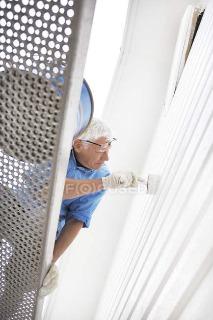 Low angle view of senior man painting wall — Stock Photo
