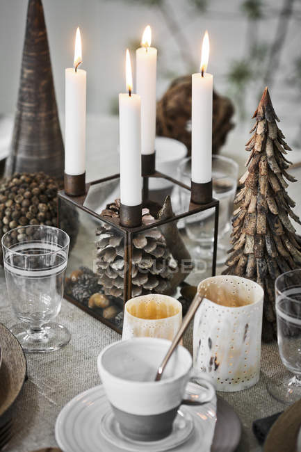 Copos e pires e velas na mesa durante o Natal — Fotografia de Stock