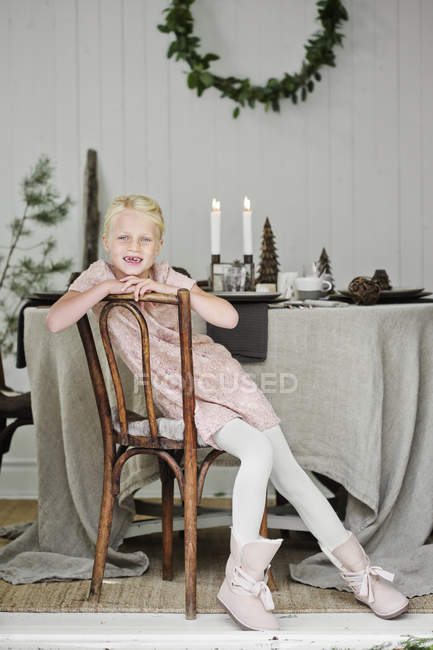 Menina sentada na cadeira na sala de estar durante o Natal — Fotografia de Stock