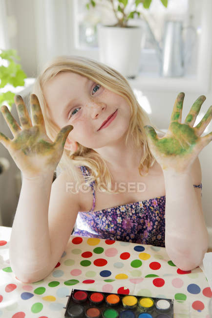 Mädchen zeigt bemalte Hände und blickt in die Kamera — Stockfoto