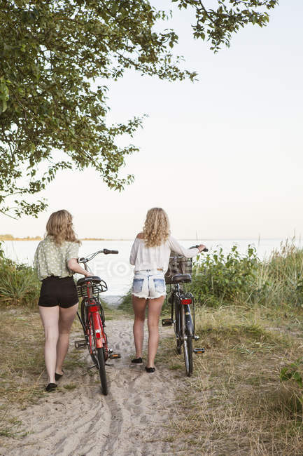 Вид сзади на двух девочек-подростков, идущих на велосипедах — стоковое фото