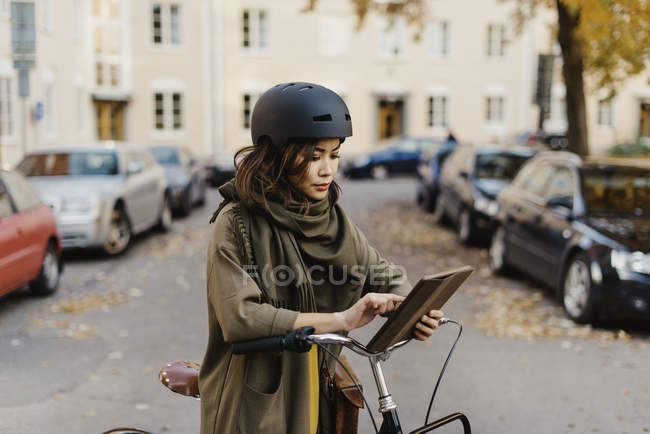Giovane donna che utilizza tablet digitale in piedi in bicicletta — Foto stock