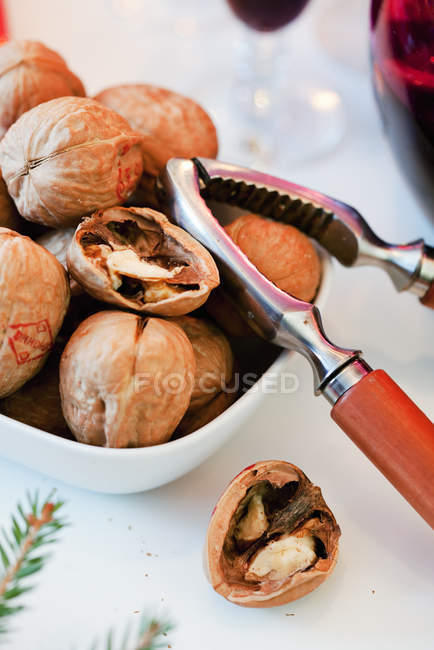 Bowls of walnuts with nutcracker on table — Stock Photo
