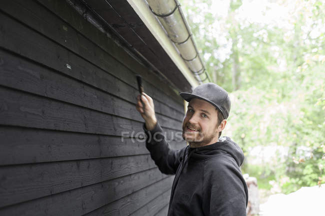 Man paining house exterior and looking at camera — Stock Photo