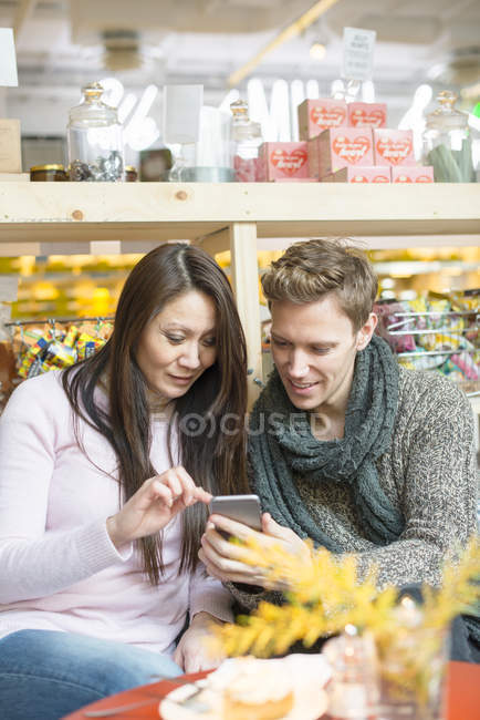 Чоловік і жінка, використовуючи смартфон в магазині, диференційований фокус — стокове фото