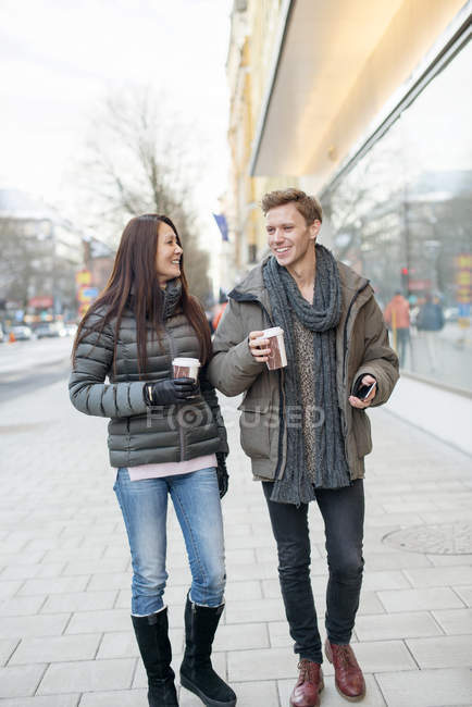 Man and woman walking in street and holding coffee in disposable cups — Stock Photo