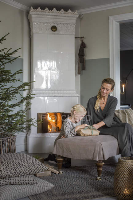 Мать и дочь сидят у камина, открывая подарки на Рождество — стоковое фото