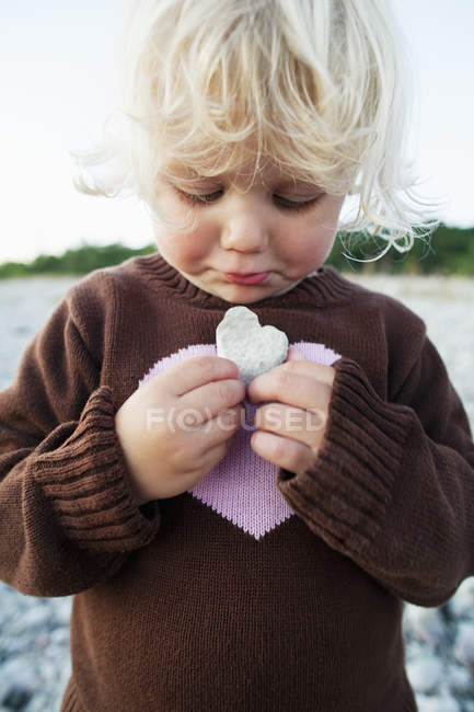 Девушка с камнем в форме сердца, сосредоточьтесь на переднем плане — стоковое фото