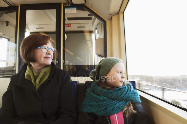 Menina sentada com a avó em bonde e olhando através da janela — Fotografia de Stock
