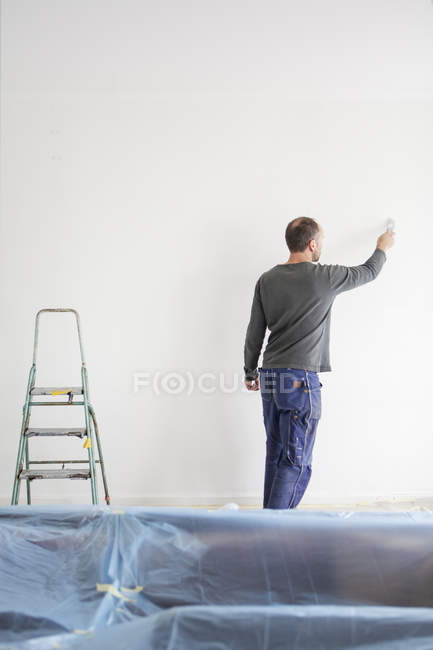 Rear view of man painting wall — Stock Photo