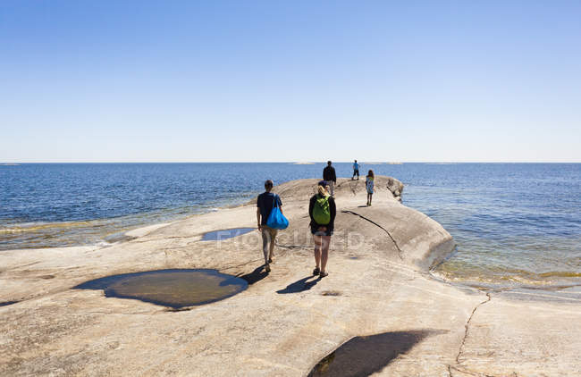 Five people walking along coastline — Stock Photo