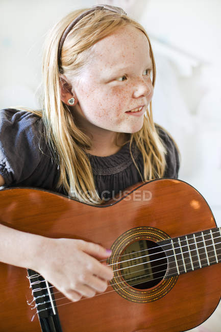 Girl with blonde hair playing acoustic guitar — Stock Photo