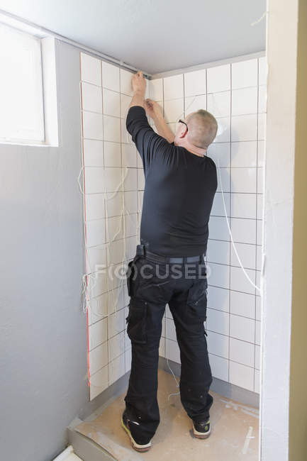 Rear view of man tiling wall — Stock Photo