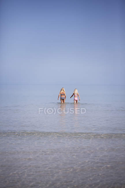 Две девушки, идущие по мелкому морю — стоковое фото