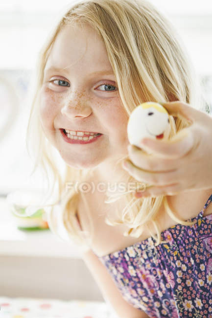 Mädchen hält Ei mit Smiley-Gesicht — Stockfoto