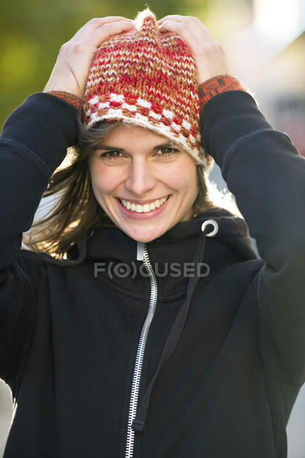 Portrait de jeune femme portant un chapeau tricoté et souriant — Photo de stock
