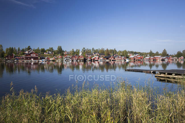 Casas rojas falu y cielo azul reflejándose en el agua - foto de stock