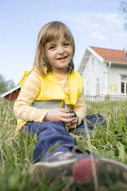 Porträt eines Mädchens, das im Gras sitzt und in die Kamera blickt — Stockfoto